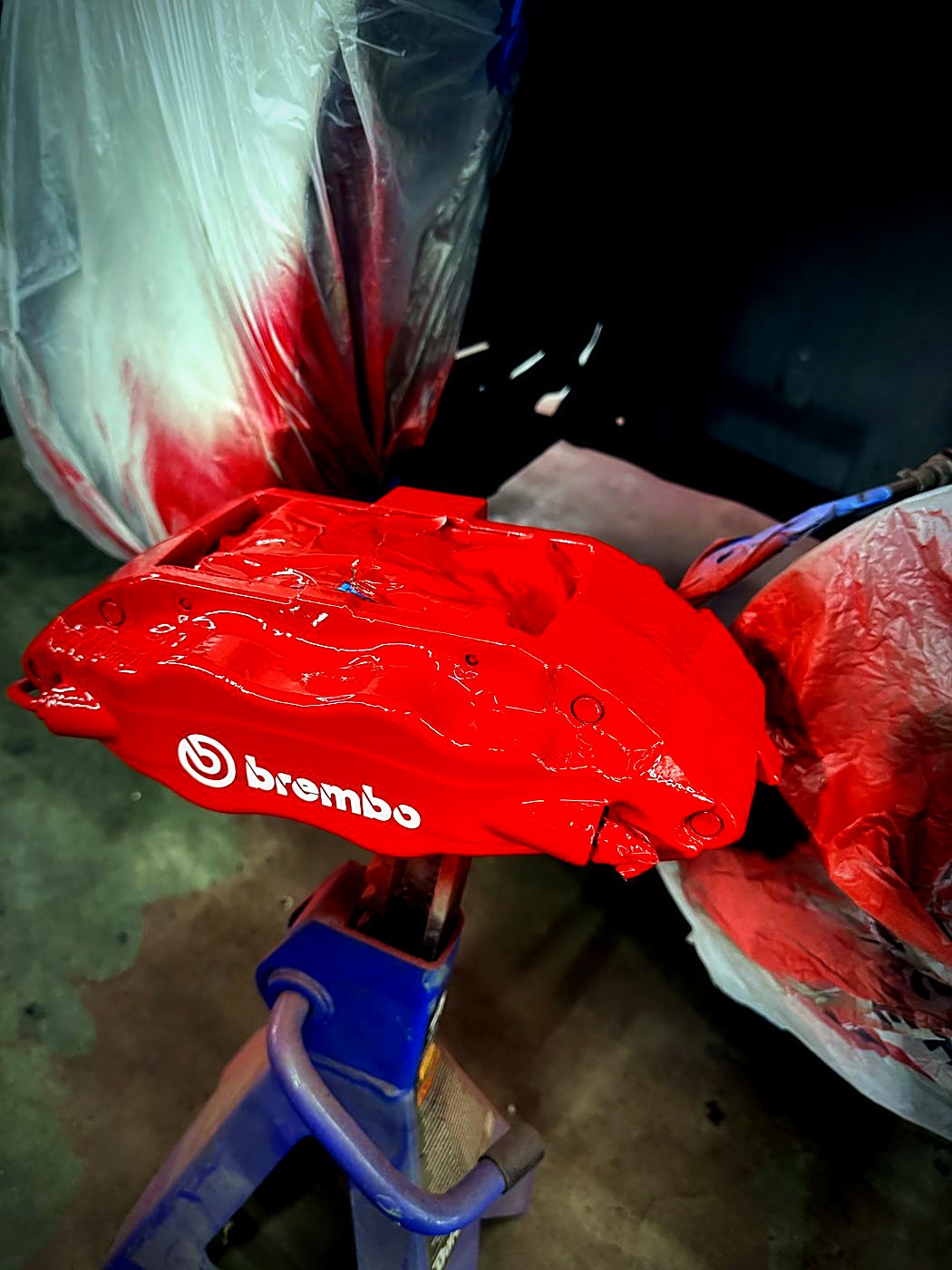 Red Brembo caliper freshly painted on stands